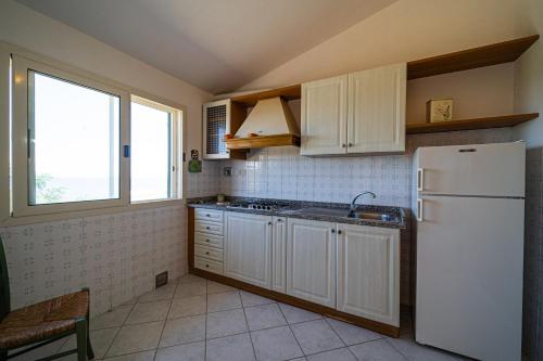 a kitchen with white cabinets and a white refrigerator at Appartamenti Vista Mare - Goelba in Capoliveri