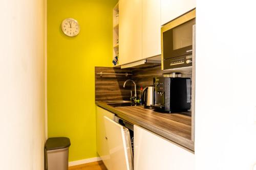 uma cozinha com um lavatório e um relógio na parede em Kuthe em Sonthofen