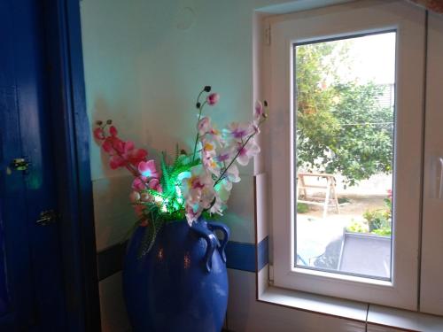 a blue vase with flowers in it next to a window at 4 Seasons Suites Paradise Athens Airport in Markopoulo