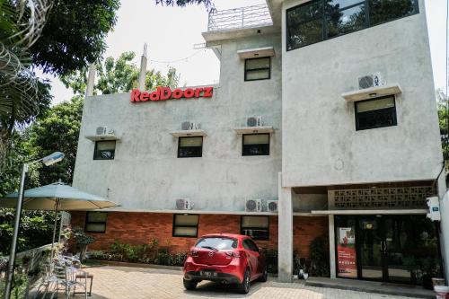 a red car parked in front of a building at RedDoorz near Trans Studio Mall Cibubur 3 in Bogor