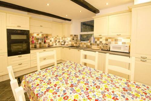 a kitchen with white cabinets and a table with a flowered table cloth at Woodland Crag Cottage, Grasmere in Grasmere