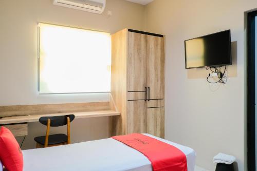 a room with a bed and a window and a television at RedDoorz near Trans Studio Mall Cibubur 3 in Bogor
