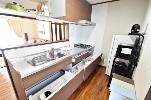 eine kleine Küche mit Spüle und Kühlschrank in der Unterkunft ゲストハウスえらぶ〜 in Wadomari