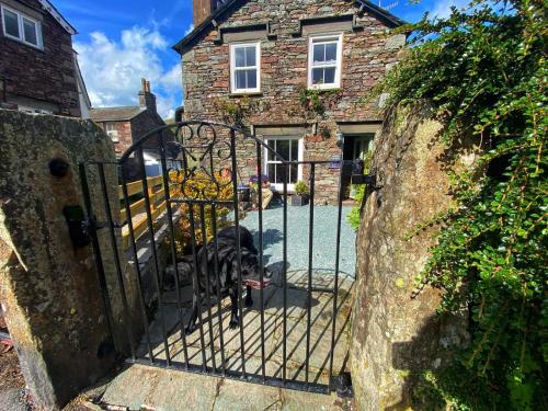 a dog standing at the gate of a house at Juniper Grasmere - Juniper Cottage, Grasmere in Grasmere