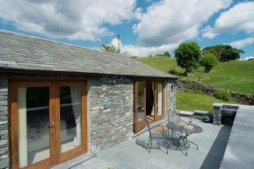 a stone house with a patio with a table and chairs at Damson View, Little Langdale in Little Langdale