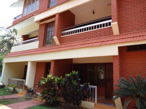 a large red brick building with a balcony at Hotel Thushara in Kovalam