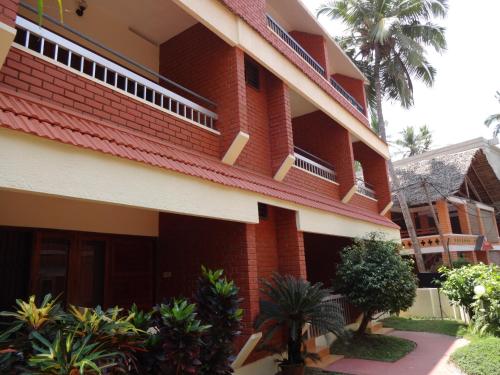 a red brick building with palm trees in front of it at Hotel Thushara in Kovalam