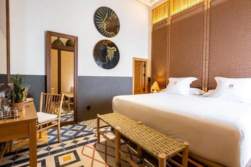 a bedroom with a large bed and a clock on the wall at Hotel La Torre del Canonigo - Small Luxury Hotels in Ibiza Town