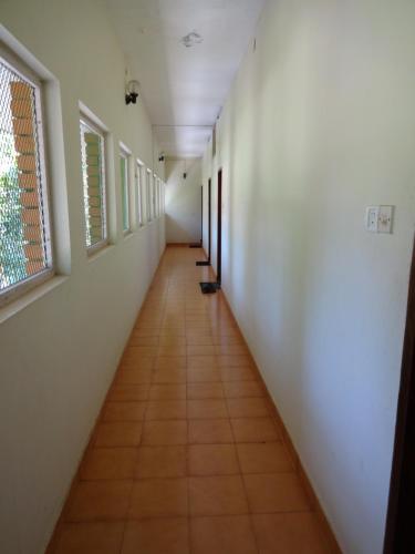 a long hallway with white walls and a tile floor at Hotel Thushara in Kovalam