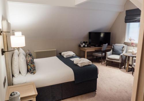 a bedroom with a bed and a desk and a television at Edgbaston Park Hotel Birmingham in Birmingham
