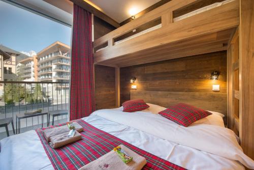 Bett in einem Zimmer mit einem großen Fenster in der Unterkunft 4Roses Apartments in Starý Smokovec