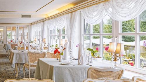 a dining room with white tables and windows at Forsthaus Seebergen in Lütjensee