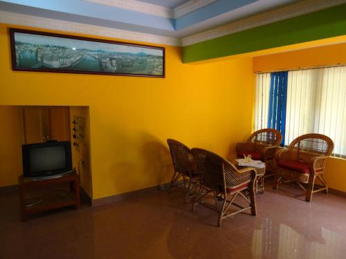 a room with chairs and a tv and a table at Hotel Thushara in Kovalam