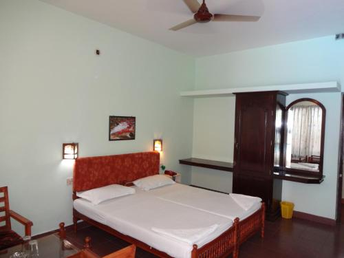a bedroom with a bed and a ceiling fan at Hotel Thushara in Kovalam