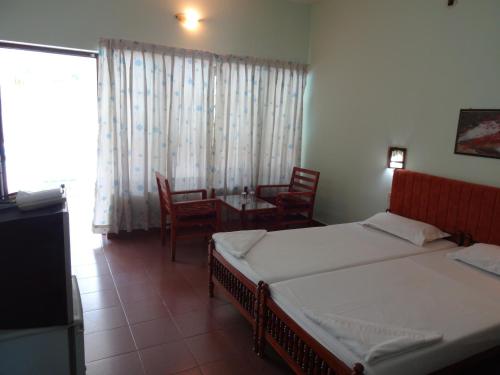a bedroom with two beds and a table and chairs at Hotel Thushara in Kovalam
