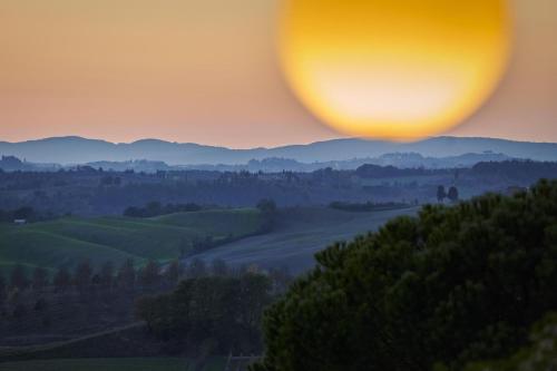 a sunset over the hills with a balloon in the sky at Villa Curina Resort in Castelnuovo Berardenga