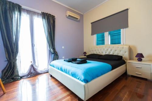 a bedroom with a bed with blue sheets and large windows at La Terra Nostra in Korinthos
