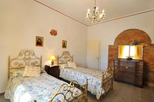 a bedroom with two beds and a dresser and a chandelier at Casale Le Capanne in Cortona