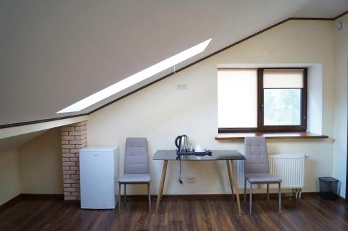 an attic room with a table and chairs and a window at Rosinka in Ukrayinka