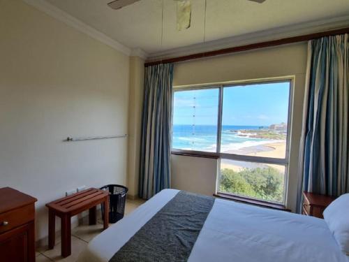 a bedroom with a large window with a view of the ocean at Santana Holiday Resort in Margate