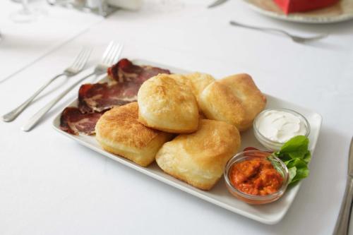 a plate of food with biscuits and dipping sauce at Hotel Vrbak ND in Novi Pazar