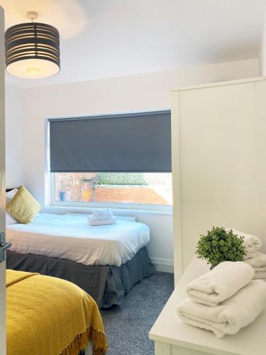 a bedroom with two beds and a window with a blue blind at The Baltic Townhouses by Serviced Living Liverpool in Liverpool