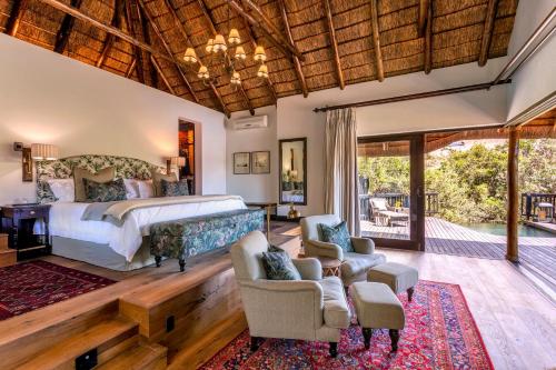 a bedroom with a bed and chairs and a patio at Lalibela Game Reserve - Kichaka Lodge in Paterson