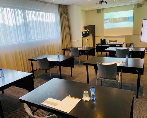 a classroom with tables and chairs and a projection screen at Mercure Hotel Den Haag Central in The Hague