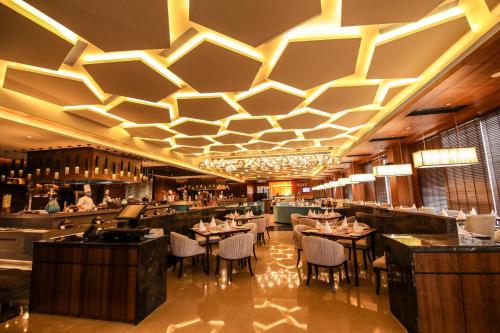 a restaurant with tables and chairs and a bar at Radisson Blu Towers Kaushambi Delhi NCR in Ghaziabad