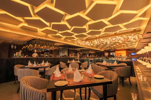 a restaurant with tables and chairs and a bar at Radisson Blu Towers Kaushambi Delhi NCR in Ghaziabad