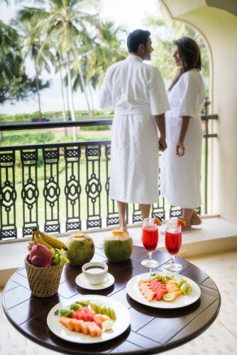 a couple standing on a balcony with a table of food at Grand Hyatt Goa in Panaji