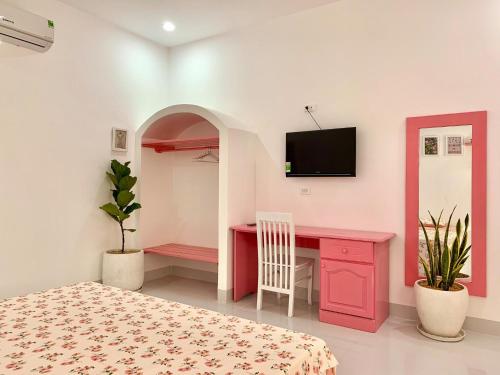 a bedroom with a pink desk and a tv on the wall at Moonbeam Homestay & Mini-resort Mui Ne in Phan Thiet