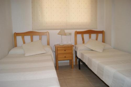 two twin beds in a room with a night stand at Residencial Sierra de Irta in Alcossebre