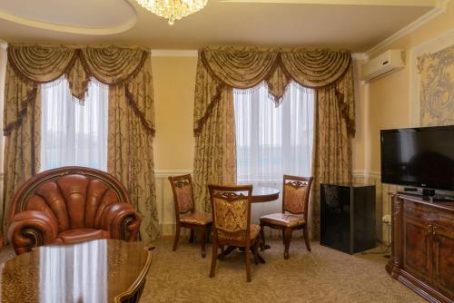 a living room with a table and chairs and a television at Versal Hotel in Maykop