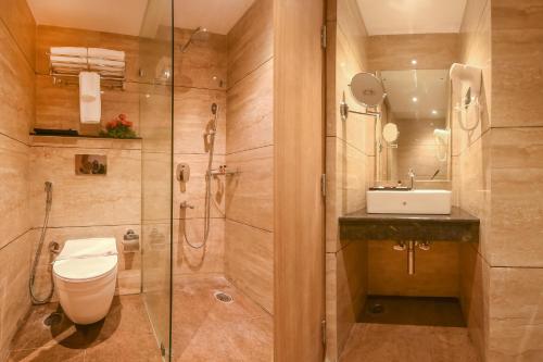 y baño con ducha, aseo y lavamanos. en Emerald Clarks Inn Suites, en Mysore