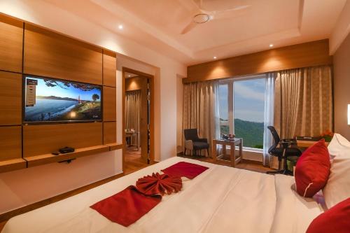 a bedroom with a large bed with a flat screen tv at Emerald Clarks Inn Suites in Mysore