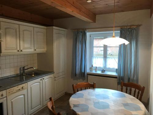 eine Küche mit einem Tisch, einem Waschbecken und einem Fenster in der Unterkunft Haus Dorfstraße in Risum-Lindholm