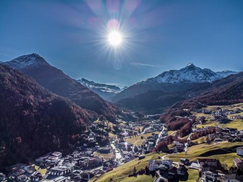 a town in the mountains with the sun in the sky at Chalets - The Peak in Sölden