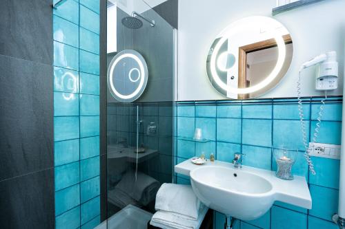 Baño de azulejos azules con lavabo y espejo en B&B Ercole di Amalfi, en Amalfi
