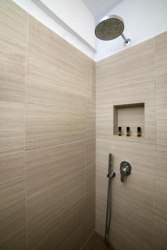 a shower in a bathroom with a beige wall at Andromeda Villas & Spa Resort in Imerovigli