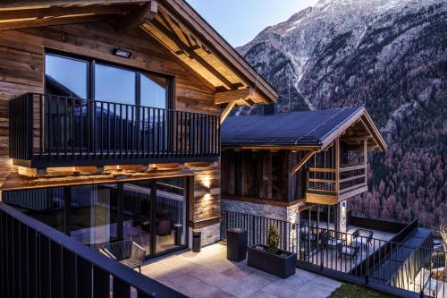 a log house with a balcony and mountains in the background at Chalets - The Peak in Sölden