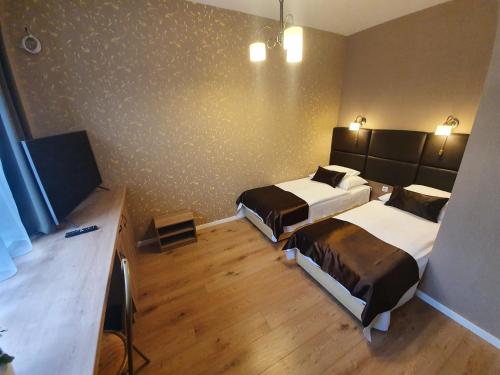 a hotel room with two beds and a television at Károlyi Panzió in Eger