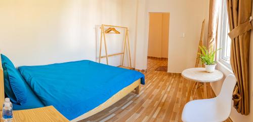 a small bedroom with a blue bed and a table at Caly homestay in Da Lat