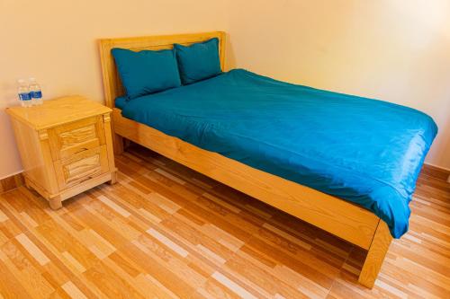 a bed with blue sheets and a night stand at Caly homestay in Da Lat