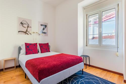 Un dormitorio con una cama con sábanas rojas y una ventana en LX Urban Living, en Lisboa