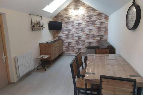 a dining room with a table and a brick wall at chalet avec jardin proche du Mont Saint Michel in Pontorson