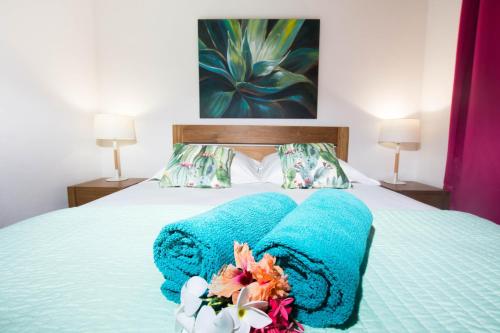 łóżko z dwoma niebieskimi ręcznikami i kwiatami w obiekcie Côté Plage w mieście Saint-François