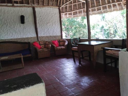 ein Zimmer mit Stühlen und Tischen in einem Restaurant in der Unterkunft Diani Banda Cottages in Diani Beach