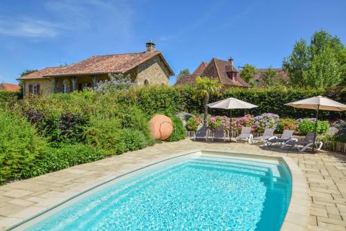a swimming pool in a yard with chairs and umbrellas at Domaine d'Essendiéras in Saint-Médard-dʼExcideuil