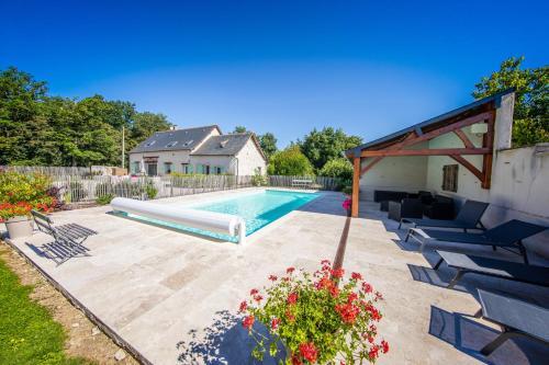 - une piscine dans un jardin avec des chaises et des fleurs dans l'établissement Métairie du Villiers, à Saint-Branchs